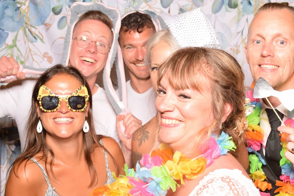 Guests smiling with colourful props in front of the photobooth